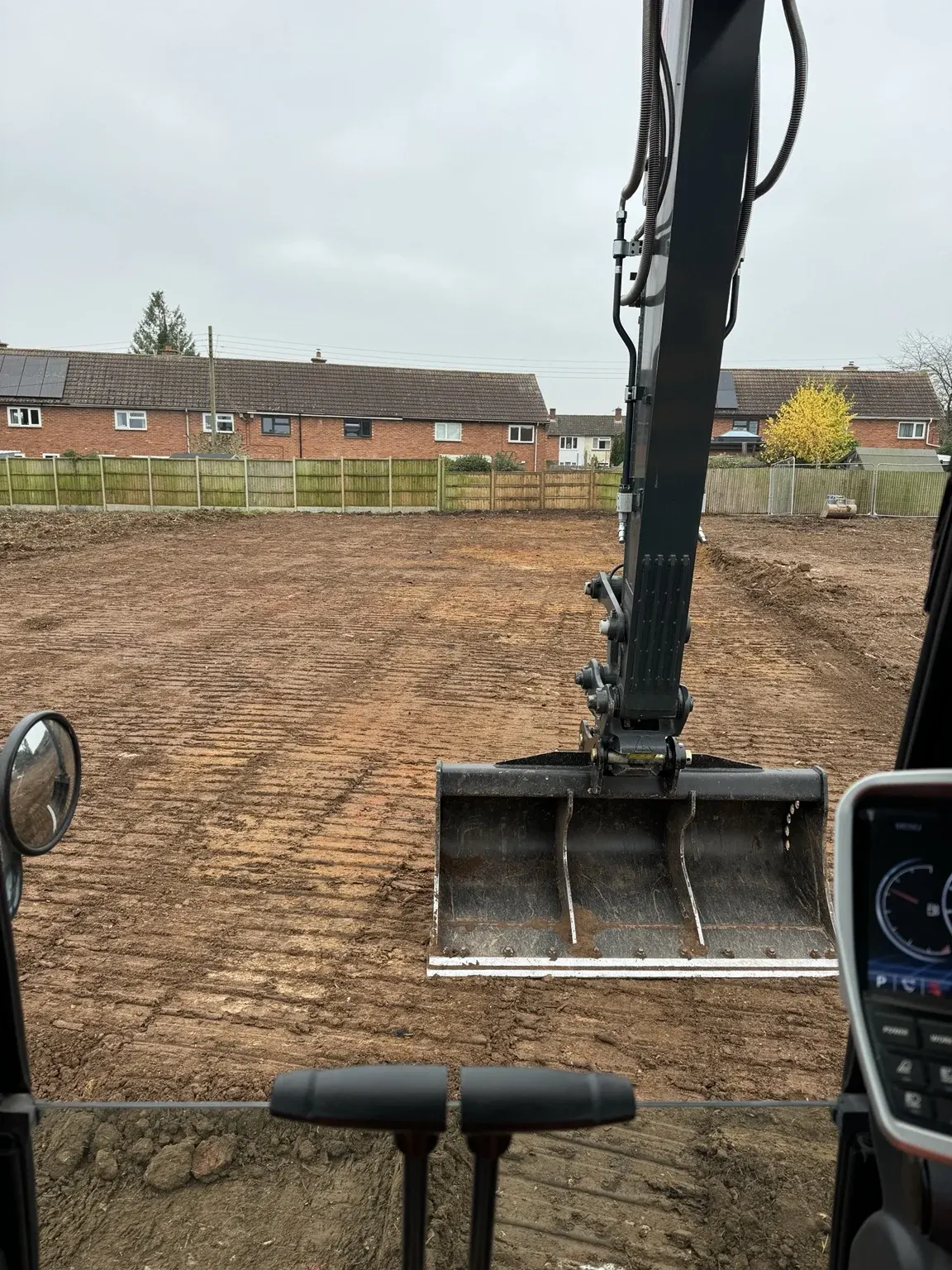View from an excavator cab during ground preparation on a residential site